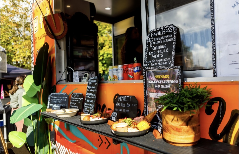 Maträtter står uppradare vid fönstret av en orange matvagn/foodtruck.
