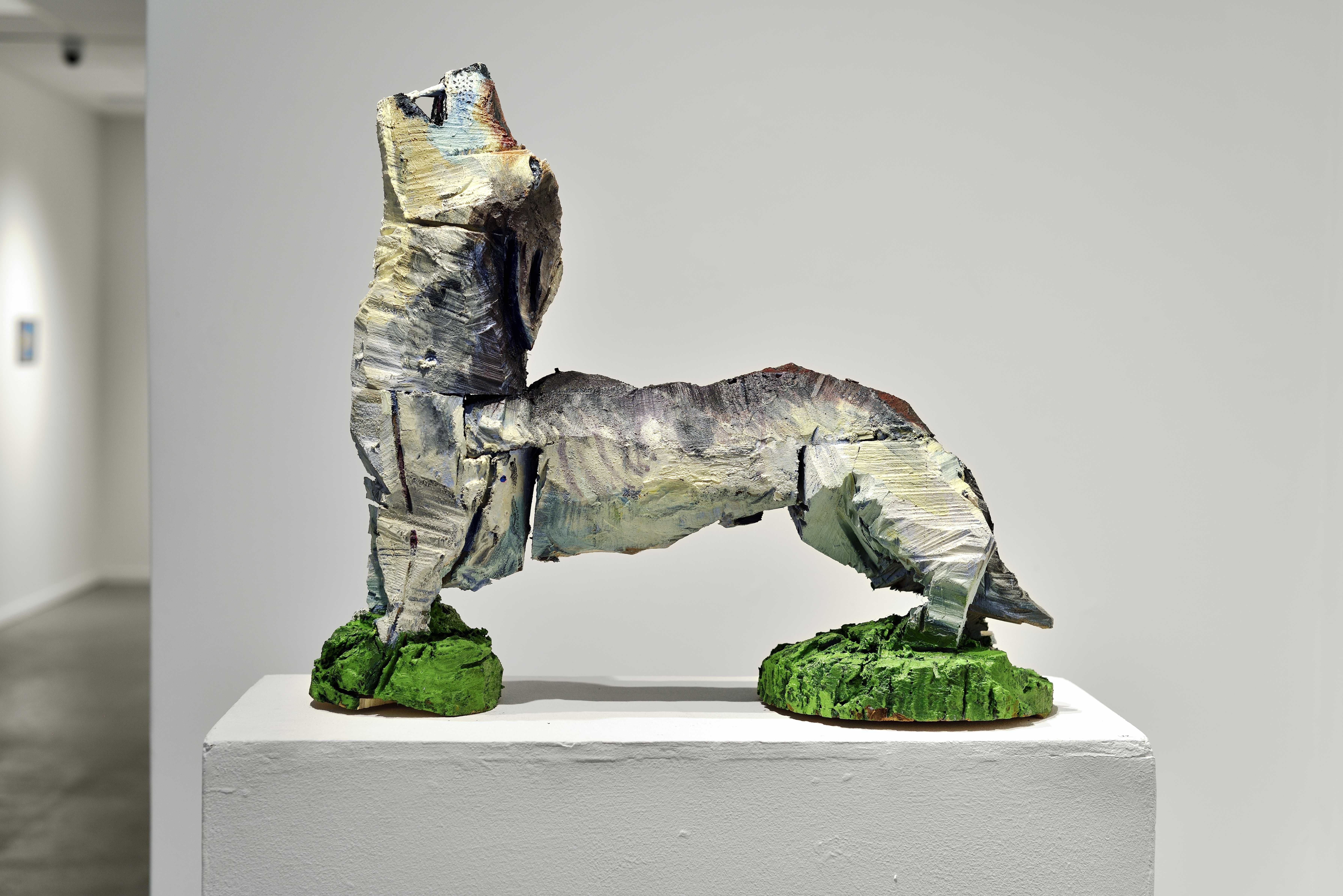 Two colorful sculptures. From one side, a painted horse is visible behind a white fence. From the other side, the piece resembles a colorful arcade game with the text