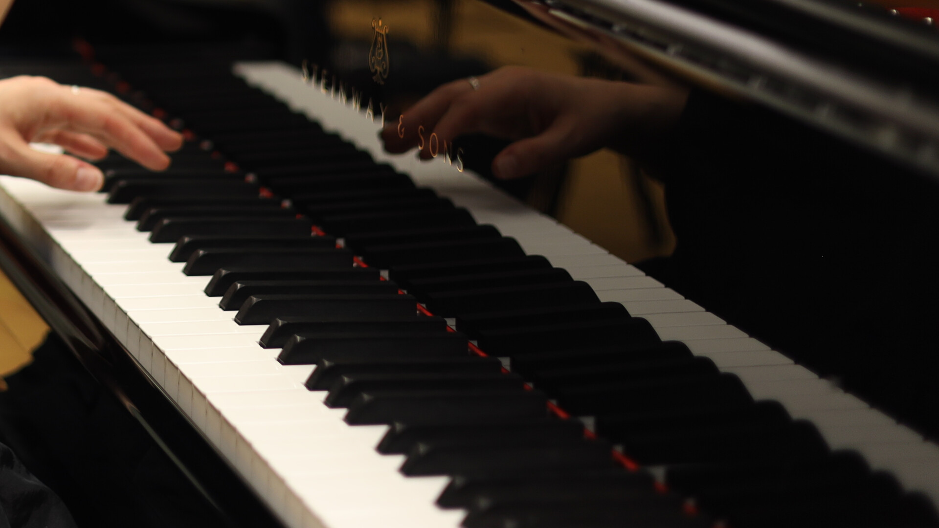 En hand syns spela på ett piano. I pianot spelas handen sväva strax ovanför tangenterna.