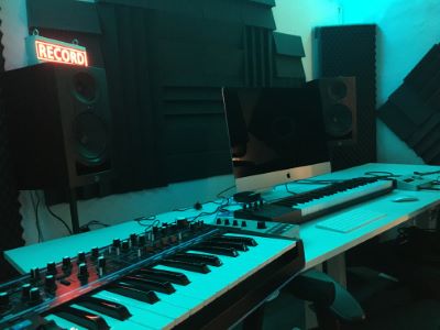 Ett piano i en musikstudio med turkost ljus.
