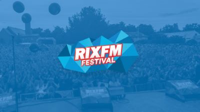En stor festivalscen med en jublande publik i bakgrunden. Den blå RIX FM Festival-loggan är centrerad i bilden.
