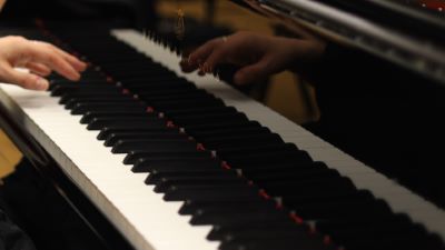 En hand syns spela på ett piano. I pianot spelas handen sväva strax ovanför tangenterna.